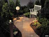 Picture of outdoor landscape lighting with a chair at the end of a brick walkway.