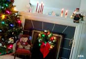 A nicely decorated fireplace at Christmas time with lights, candles and a teddy bear 