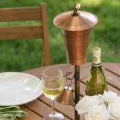 Picture of a copper tiki torch on an outdoor table.
