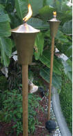 Picture of two gas tiki torches in a garden.